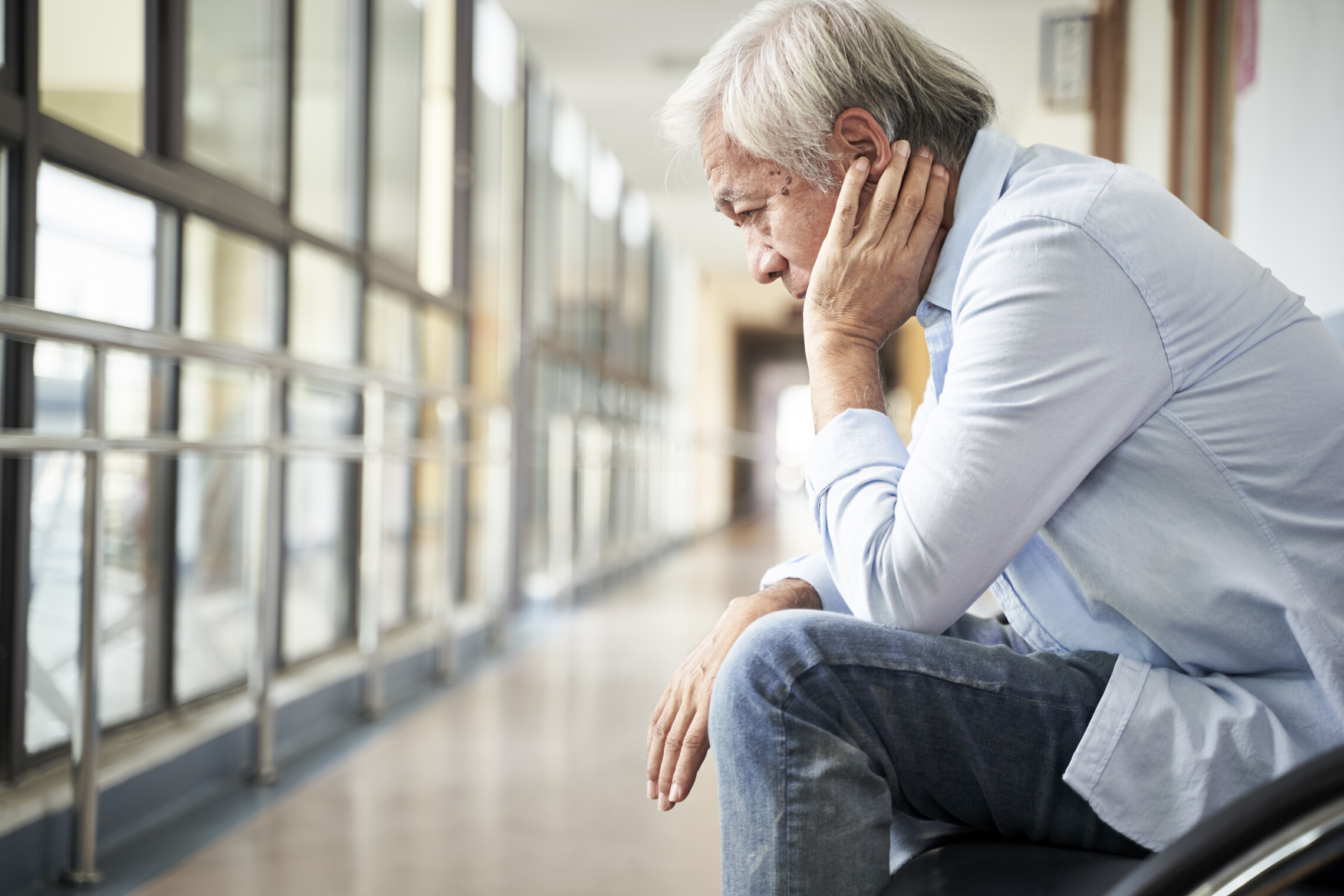 Person sitting in hospital hallway looking sad and depressed